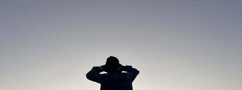 Person balancing on one leg in a wide, open space during sunrise.